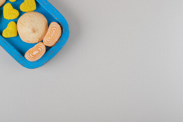 Cookies and marmelades arranged on a blue platter on marble background