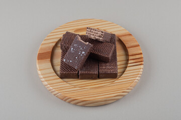 Chocolate wafers bundled together on a wooden platter on marble background