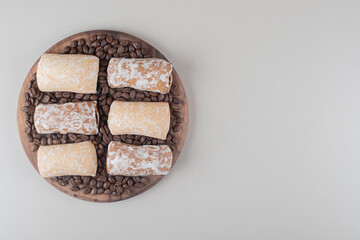 Cookie wrappings and coffee beans on a wooden board on marble background