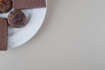 Chocolate coated wafers and chocolate chip cookies on a platter on marble background