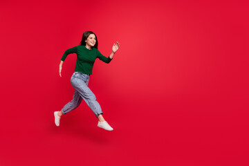 Full body photo of cheerful cute woman model run speed hurry buyer dressed stylish green clothes isolated on vivid red color background