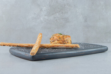 A small sour gogal next to stick crackers on a board on marble background