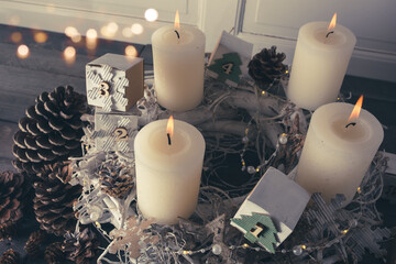 Four white candles on an old wooden background. Atmospheric Christmas decorations with self-made...