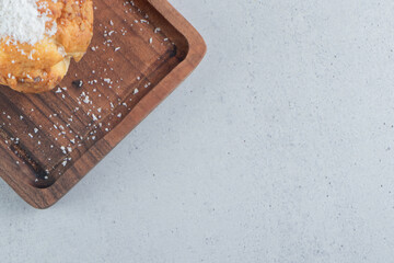 Vanilla powder topped cake on a wooden tray on marble background