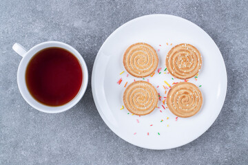 Cup of tea and delicious biscuits on white plate