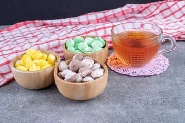 Delicious candies and cup of tea on marble surface