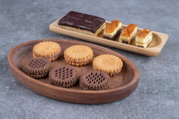 Bunch of delicious biscuits and cake slices on wooden plates