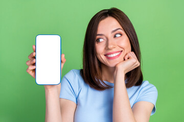 Photo of positive pretty girl look hand hold empty space telephone display isolated on green color...