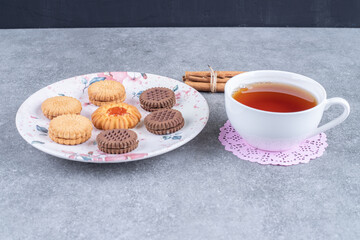 Various biscuits on plate with cup of hot tea