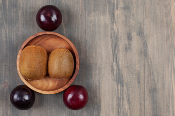 Juicy plums with kiwi on a wooden table