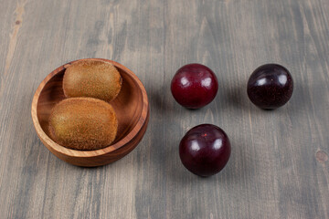 Juicy plums with kiwi on a wooden table