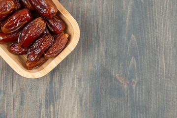 Juicy dates in a wooden plate on a wooden table