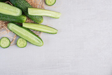 Whole and chopped cucumbers on stone surface