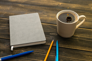 mug of coffee on the table next to the diary with a pen and pencil in the morning