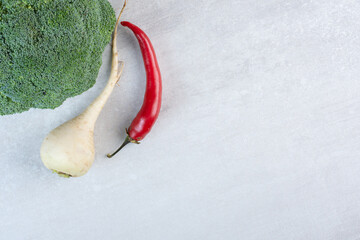 White turnip, broccoli and chili pepper on stone surface