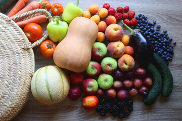 Fototapeta Round straw bag and various healthy fruits and vegetables on wooden background. Top view. obraz