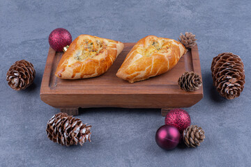 Fototapeta na wymiar Delicious pastries with Christmas balls on a wooden board