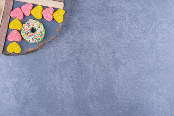 Fototapeta na wymiar A dark plate full of donuts and heart shaped jelly candies