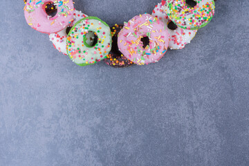 Colorful sweet fresh donuts on a gray background