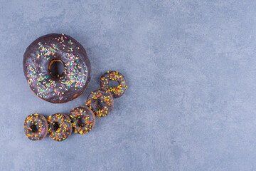 Big chocolate donut with many small chocolate donuts