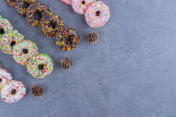 Many of delicious donuts with pinecones on a gray background