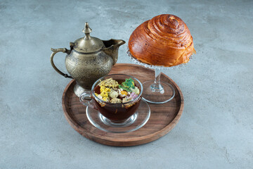 Cup of tea, teacup and pastry on wooden plate