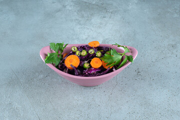 Slices of various vegetable and greens in pink bowl