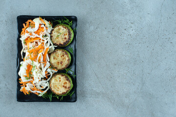 Chopped cabbage and carrots with grilled pepper on black plate