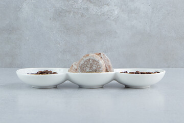 Serving platter with coffee beans and cookies on marble background