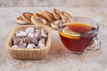 Cup of tea, crackers and bowl of sweets on marble background