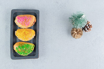 Platter with buns next to a tree figurine and pine cones on marble background