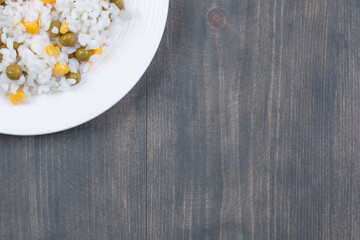 Rice with canned corns and peas on white plate