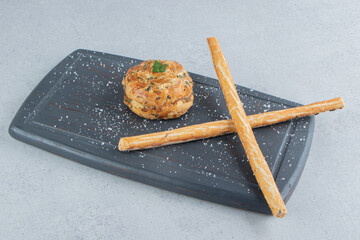A small sour gogal next to stick crackers on a board on marble background