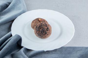 Chocolate chip cookies on a white platter next to table cloth on marble background