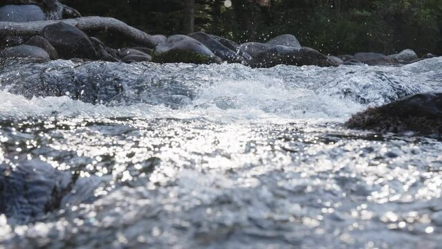 Slow motion pan across water that is gurgling down a stream.