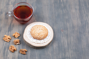 Cup of tea, cookie and walnut kernels on wooden surface