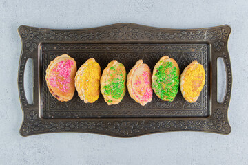 Bundle of small buns with various toppings on an ornate tray on marble background