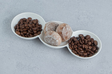 Serving platter with coffee beans and cookies on marble background