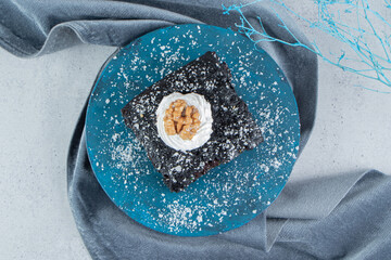 Chocolate cake coated with vanilla powder on a small board on marble background