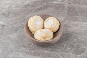 Flaky cookies in a small bowl on marble background