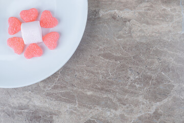 Heart marmelades around a marshmallow on a platter on marble background