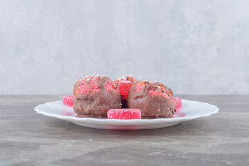 Marmelades and tiny cakes on a platter on marble background