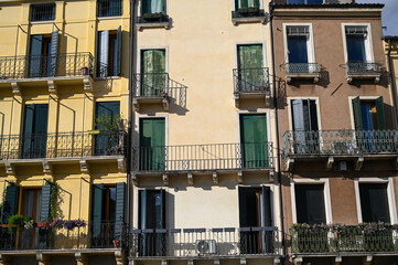 Fototapeta na wymiar Windows and balconies on colorful building in city centre. Buildings and houses in city of Padua, Italy. Architecture in Tuscany. 