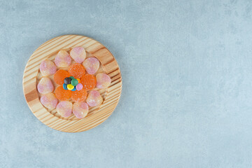 Platter of assorted marmelades with a few pieces of candy on marble background