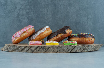 Assortment of donuts on a wooden board on marble background