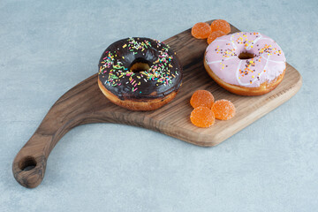 Marmelade bundles and two donuts on a wooden board on marble background