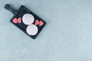 Black wooden tray with marmelades and cookies on marble background