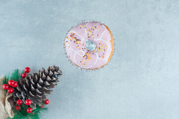 Single donut next to a christmas ornament on marble background
