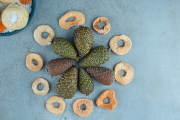 Dried apple slice circle, pine cone bundle and a platter of cookies and marmelades on marble background