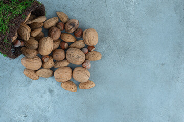 Bundle of nuts pouring out of a fancy bowl on marble background